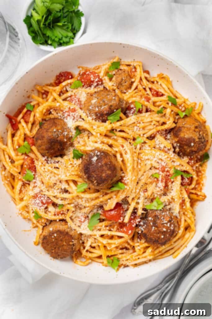 Ultimate Keto Spaghetti and Meatballs 3 Keto spaghetti and meatballs on a plate with parmesan cheese and chopped parsley.
