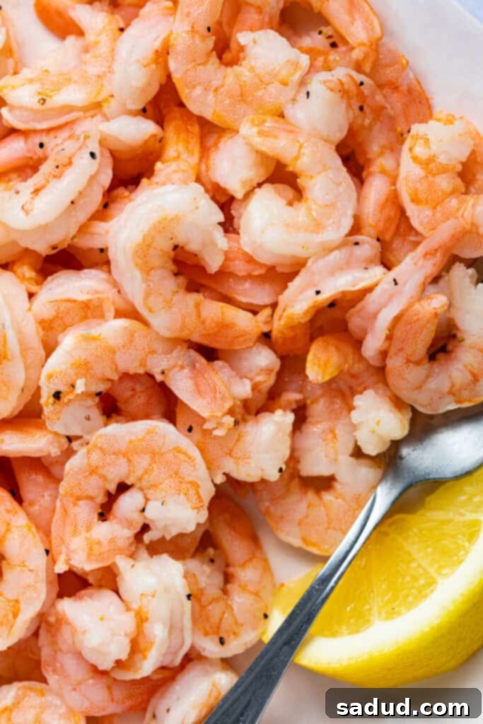 Close-up image of cooked shrimp with a lemon wedge.
