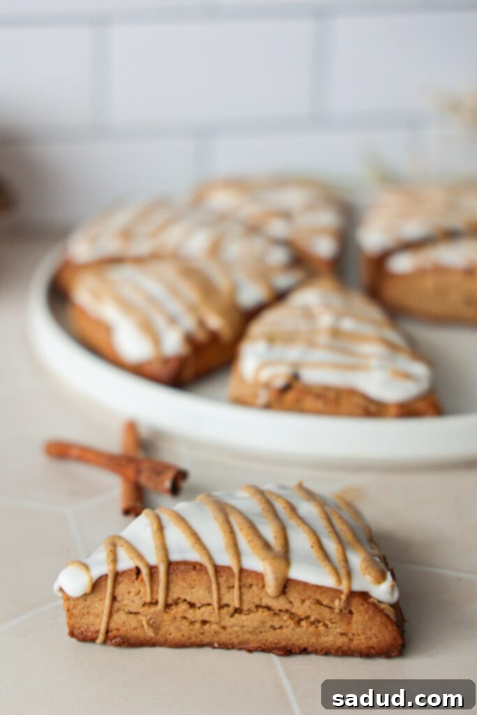 Gluten-Free Harvest Pumpkin Scones 2 gluten-free pumpkin scones with maple glaze on a white plate