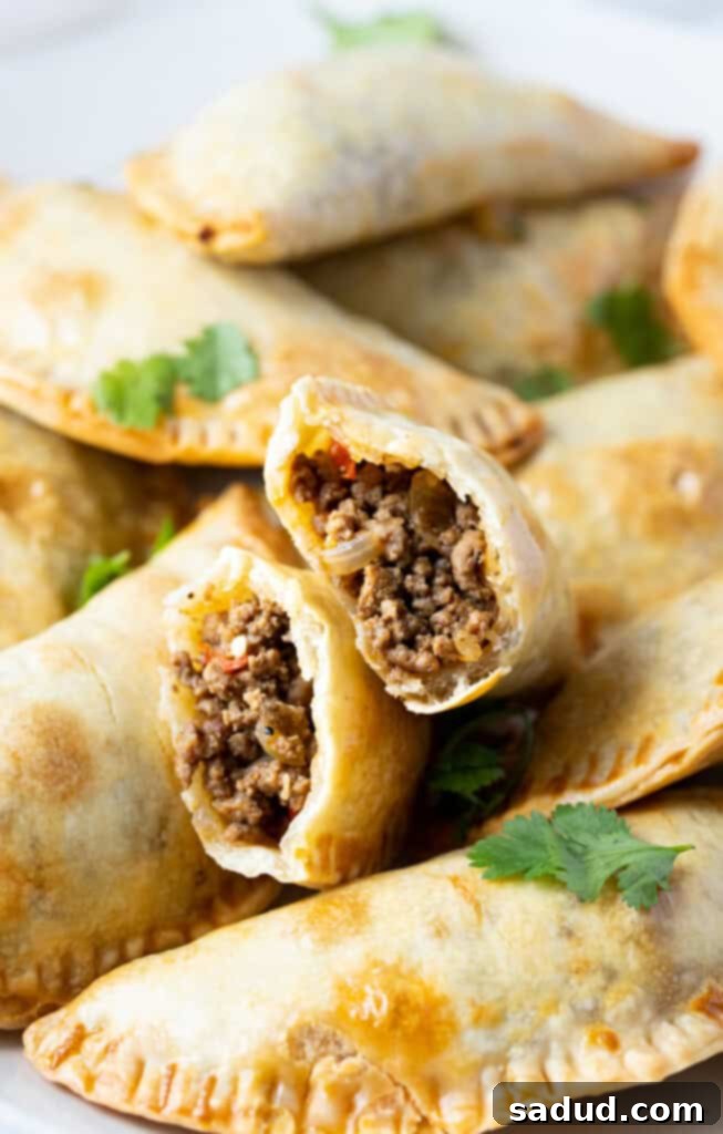 Air fryer empanadas torn in half to show ground beef inside
