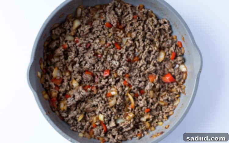 Ground beef with onion, beef broth, bell pepper, and spices in skillet