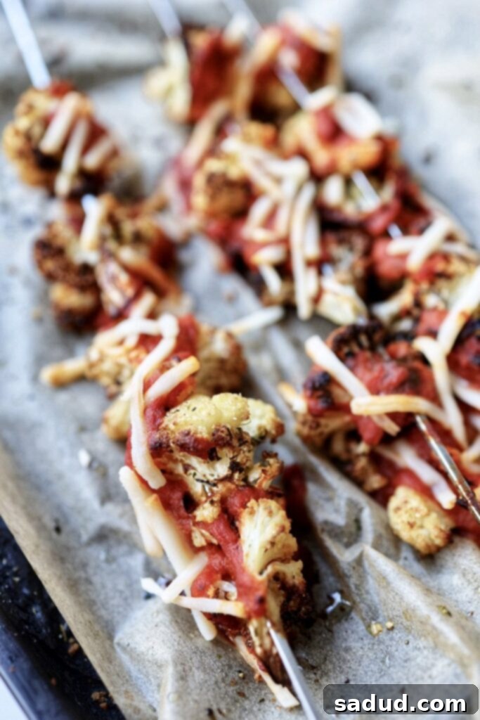 Skewers of cauliflower covered with pasta sauce and shredded cheese.