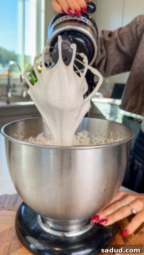 Process of making homemade marshmallow fluff for the S'mores tart, showing ingredients in a mixer.