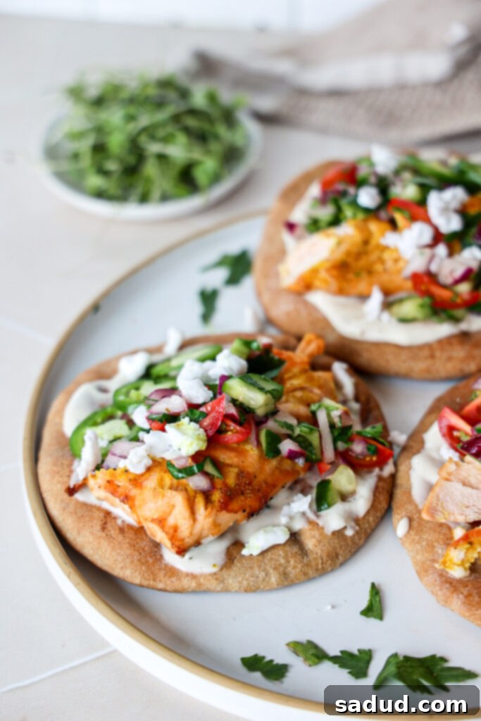 Whip Up Naan Tacos 2 salmon naan tacos - A close-up of two naan tacos filled with flaky salmon, fresh Greek salad, and a creamy white sauce, garnished with herbs.