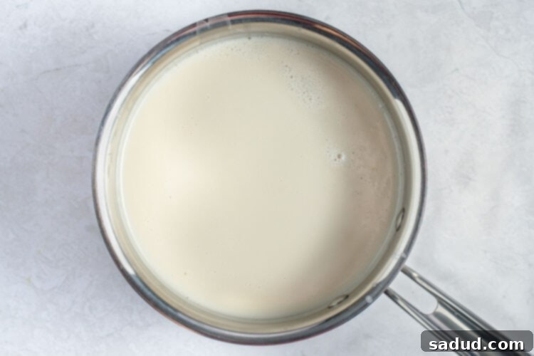 Coconut milk and almond slurry thickening in a large saucepan.