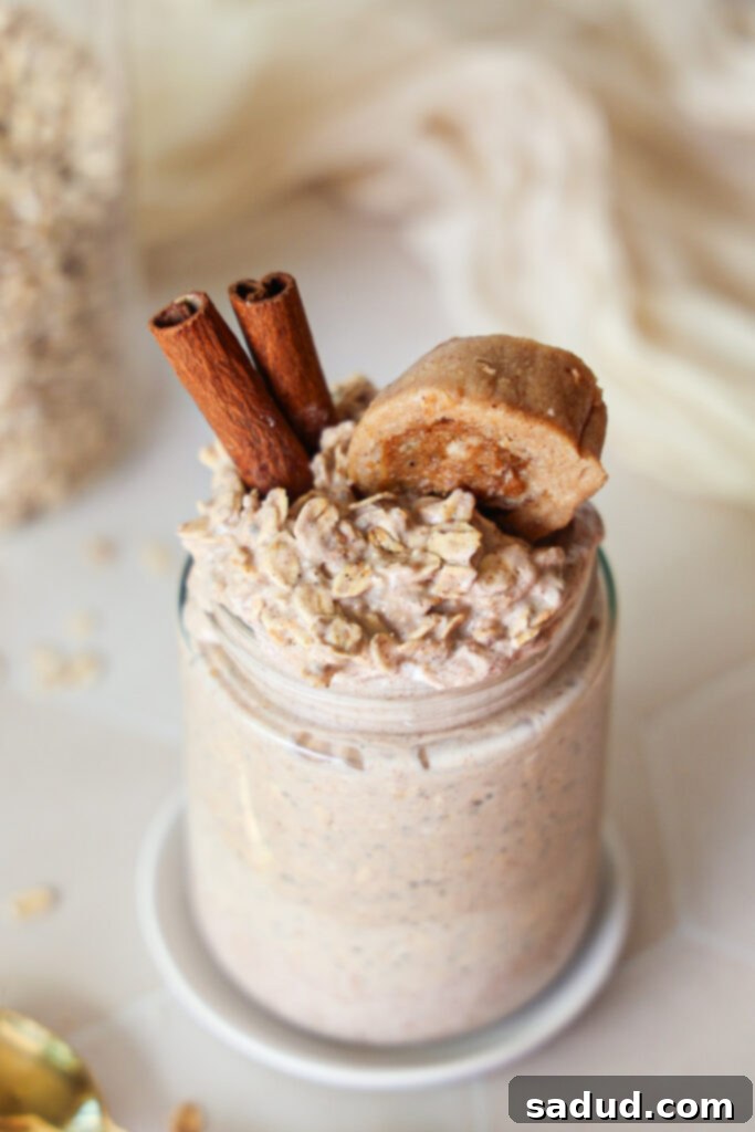 A jar of cinnamon roll overnight oats with a spoon, ready to eat.