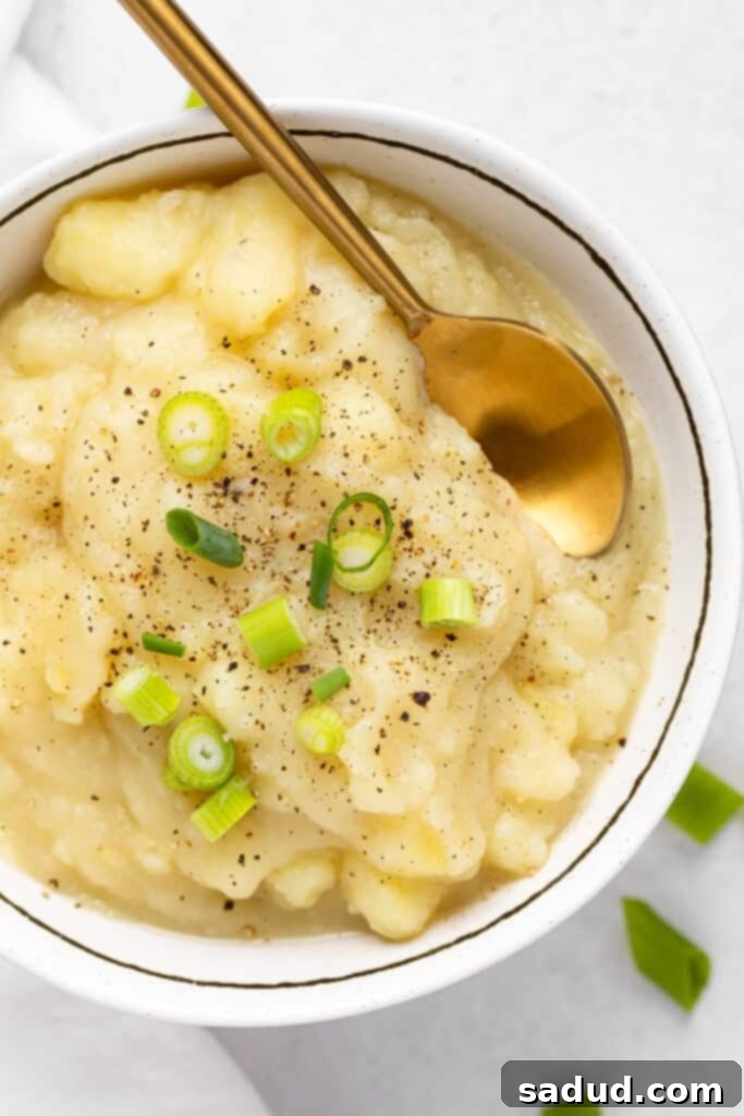 overhead of stewed potatoes topped with green onion and black pepper.