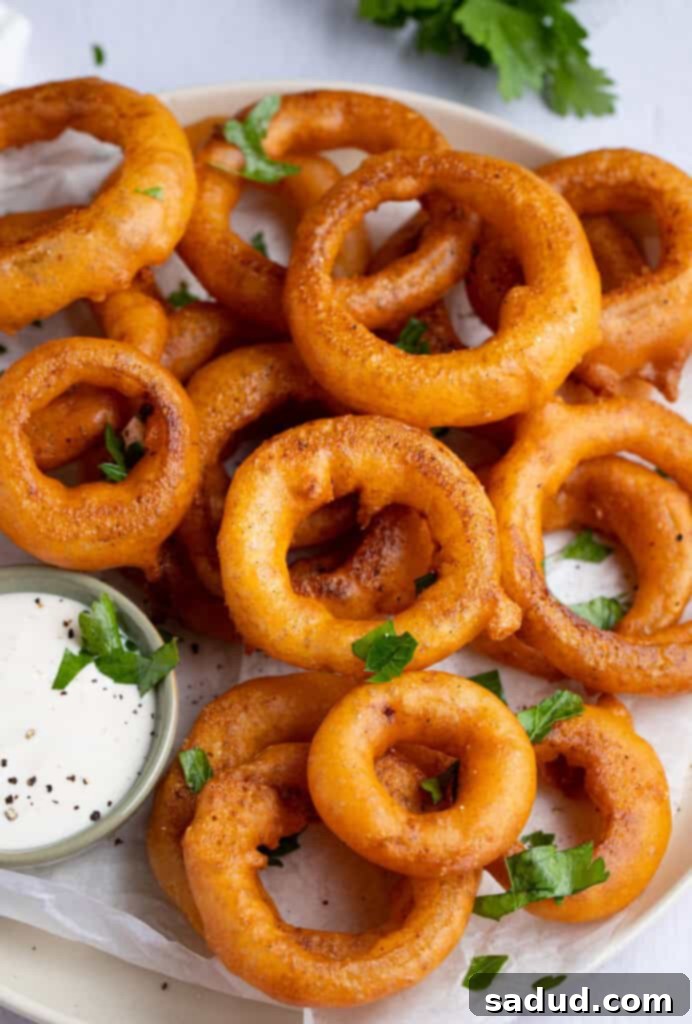 Crispy Gluten-Free Onion Rings 2 Gluten free onion rings on a plate next to a small dipping bowl of ranch dressing