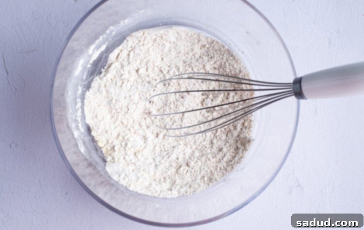 Dry ingredients for gluten free onion ring batter in a large glass mixing bowl with a whisk