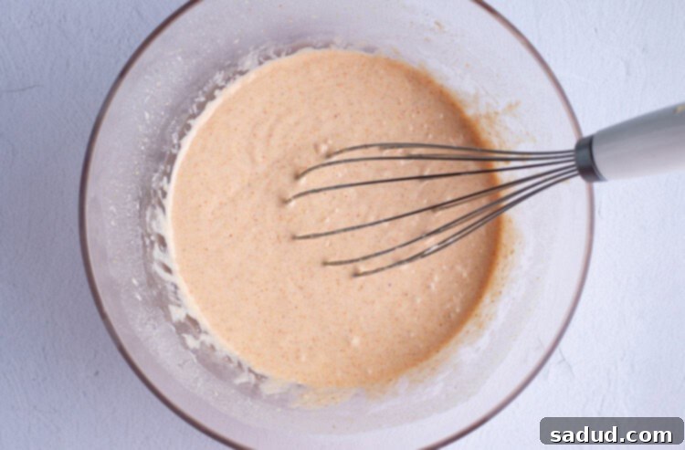 Gluten free onion ring batter in large glass mixing bowl with whisk