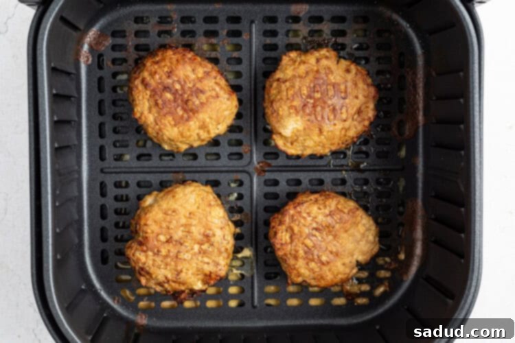 Turkey burger patties are carefully placed in the air fryer basket and cooked at 360°F for 15 minutes, with a flip midway through cooking.
