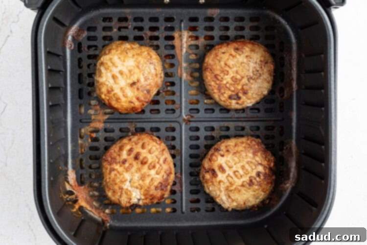 Pre-made turkey burger patties are placed in an air fryer basket and cooked, illustrating the convenience of store-bought options.