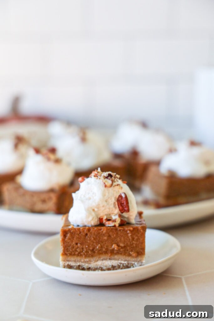 A gluten-free, paleo pumpkin pie bar with whipped cream and pecans.