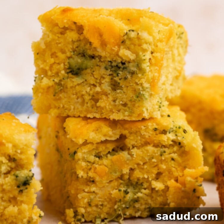 Two squares of broccoli cornbread, stacked one on top of the other, revealing its moist interior and cheesy topping.