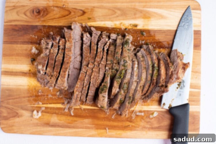 Sliced flank steak on a cutting board with a sharp knife
