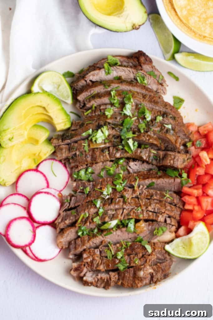 Zoomed out photo of sliced Instant Pot carne asada on a white plate sitting on a white table