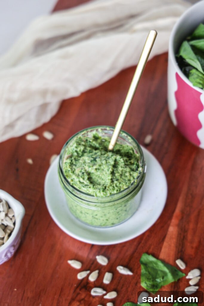 Nut-free pesto. A close-up of superfood pesto in a glass jar with fresh basil leaves.