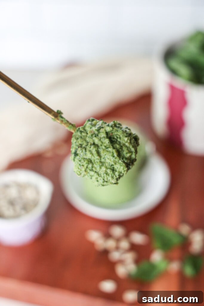 Healthy, easy homemade pesto. Nut-free, vegan. A spoonful of superfood pesto being scooped from a jar.