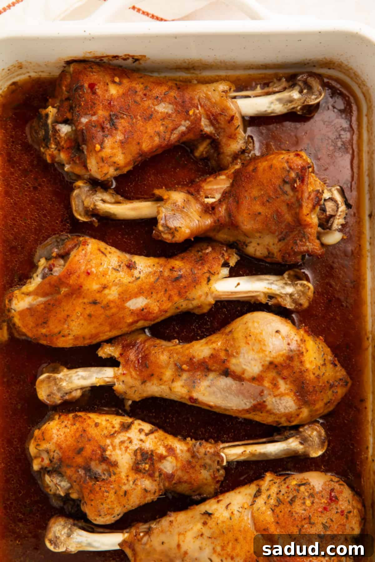 Succulent Oven-Roasted Turkey Drumsticks 2 Six beautifully roasted turkey legs glistening with pan gravy, covered in a golden-brown spice rub, served in a large roasting pan.