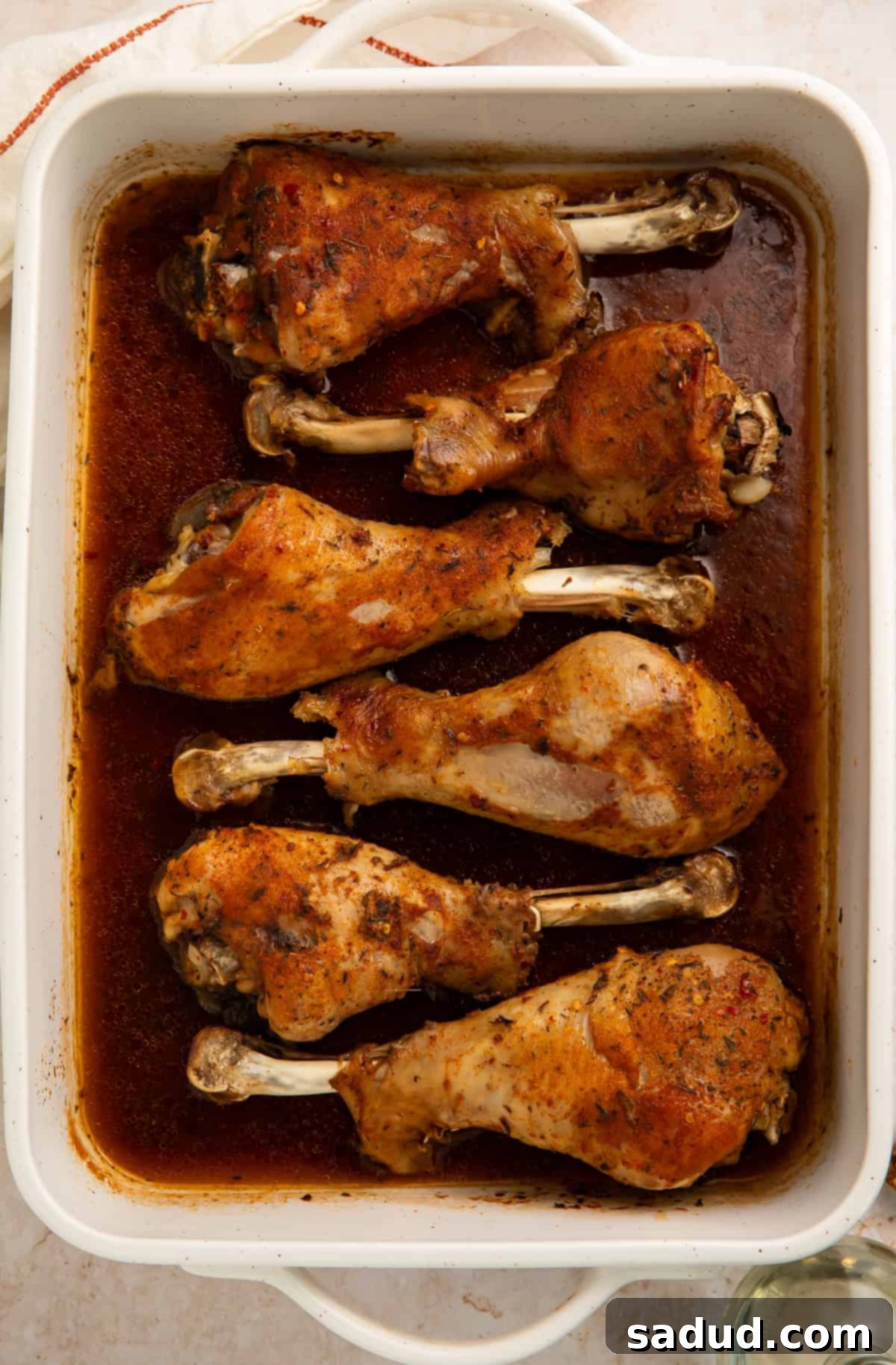 Succulent Oven-Roasted Turkey Drumsticks 3 White baking dish with six turkey legs nestled in a pool of gravy, ready to be served.