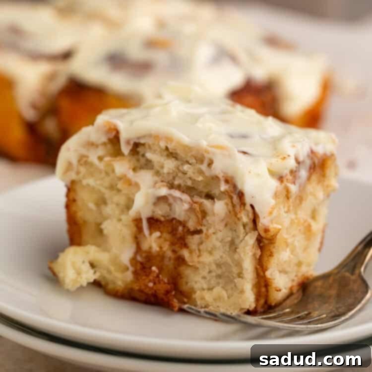 Healthy cinnamon roll on a stack of white plates with a fork.