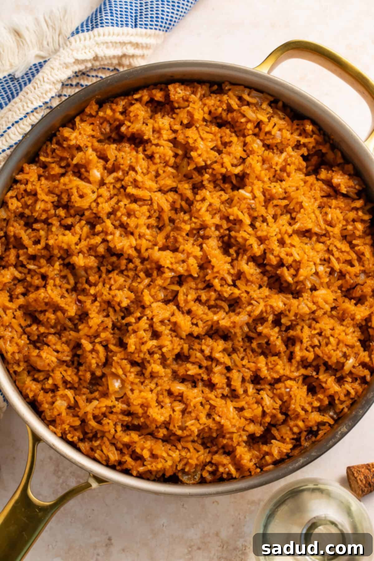 Texas Roadhouse Inspired Rice Pilaf 3 Pan of seasoned rice with a blue and white kitchen towel on one side.